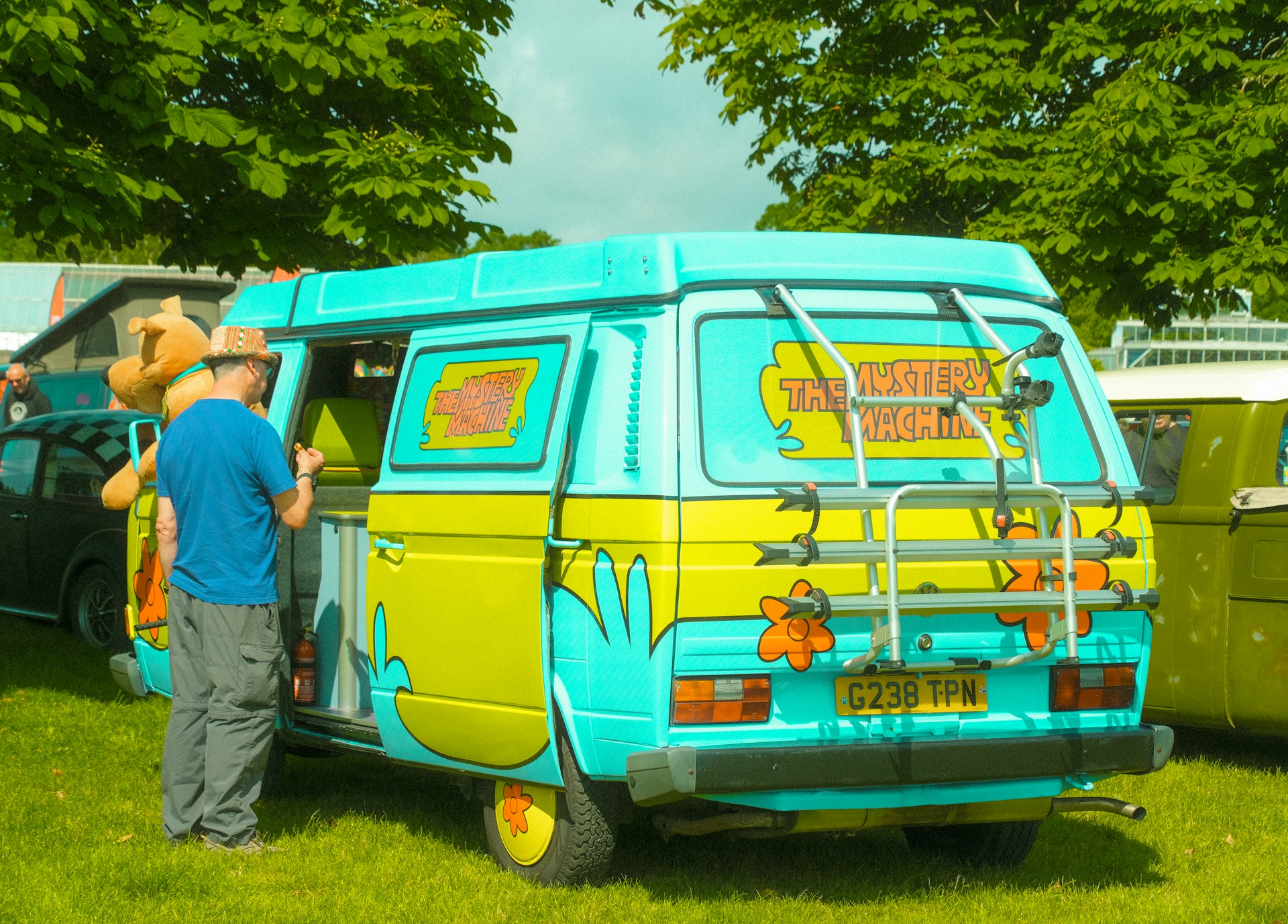 a man standing in front of a van with a stuffed animal on top of it